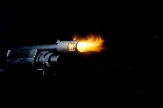 a rifle with flash emitting from the gun barrel